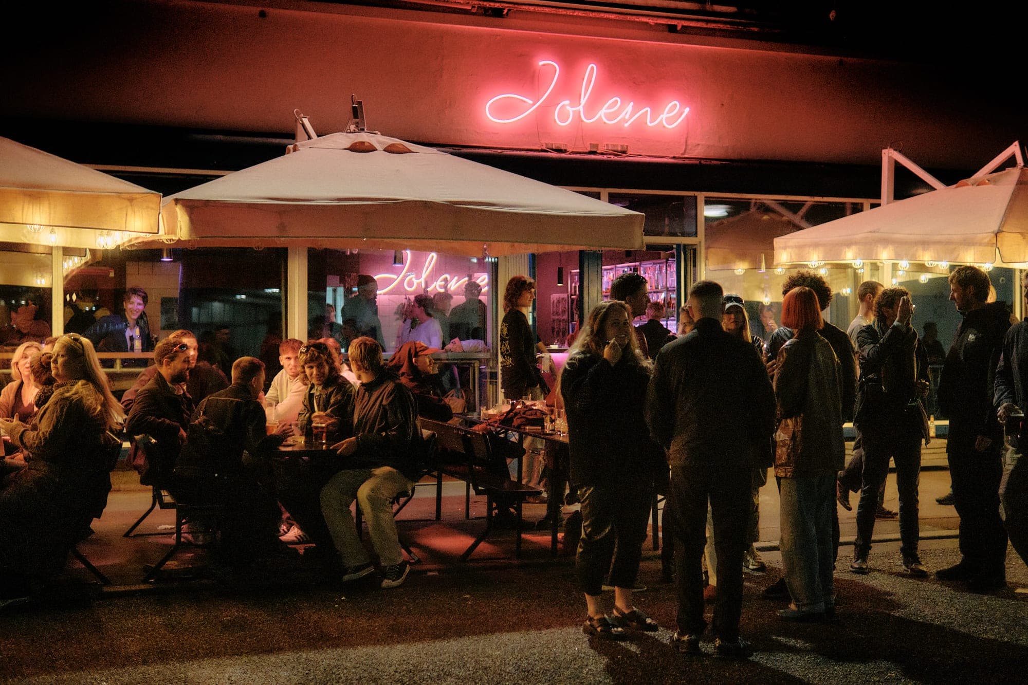 Guests outside Jolene in Kødbyen, Copenhagen, at night, under the pink neon Jolene sign