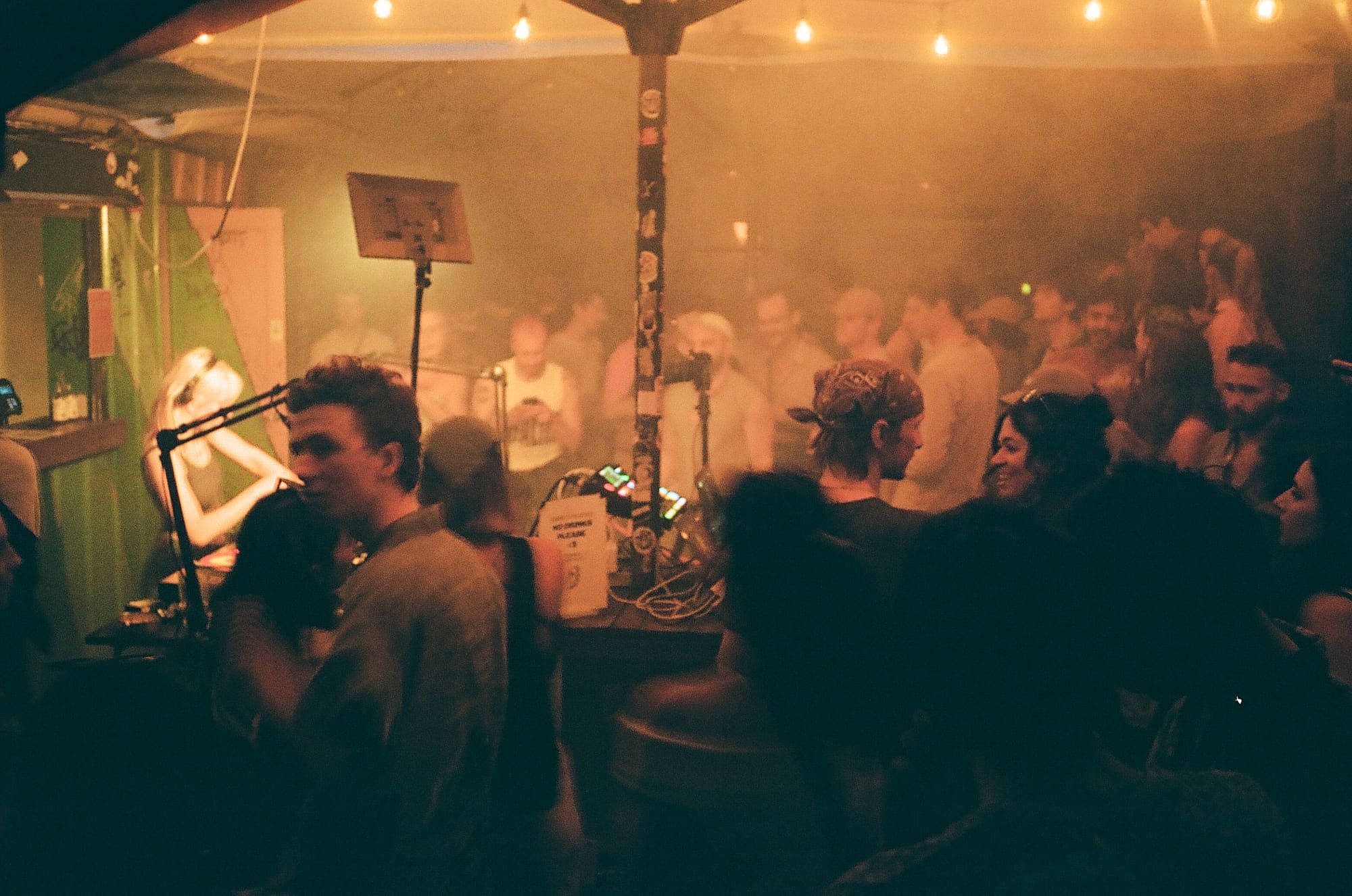 A packed, smoky backyard session at Baggen in Copenhagen, with a radio microphone on a stand beside the DJ booth